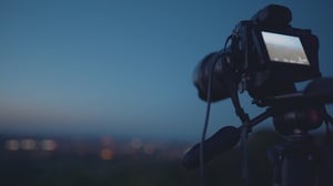 Cámara fotográfica y de video sobre un tripié con una vista panorámica de fondo.