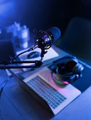 Micrófono y computadora sobre un escritorio como parte de la preparación en la producción de un podcast | House of Films