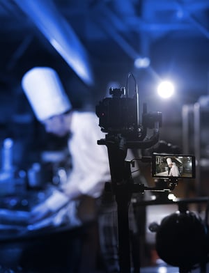 Cámara de video en primer plano grabando a una persona cocinando en un set en una transmisión LiveStream | House of Films