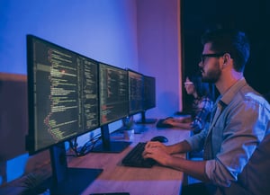 Personas trabajando en una computadora mostrando código de programación en los monitores. Neracode ofrece talento en desarrollo de software con el servicio IT Staff Augmentation.